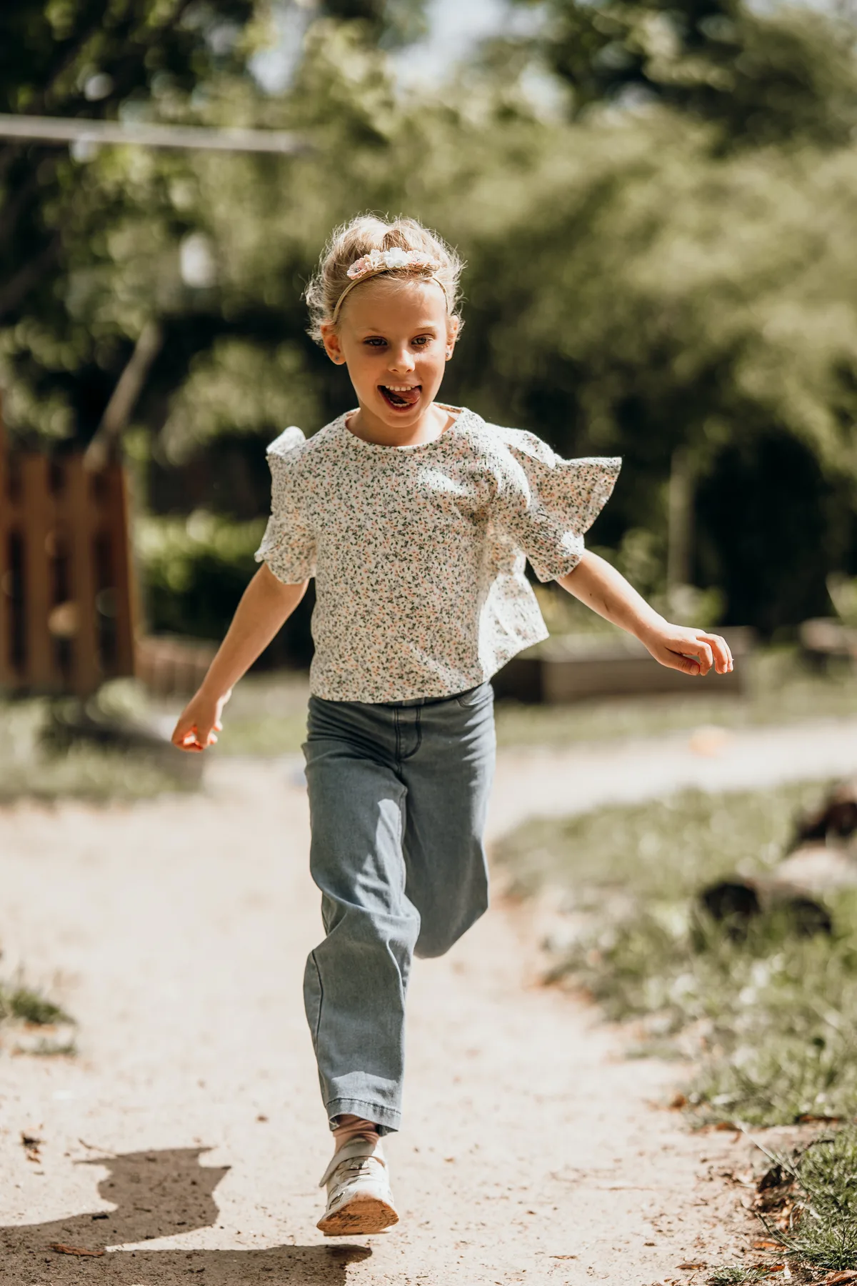 Kindergartenfoto: Rennendes Mädchen lacht ausgelassen im Sonnenlicht