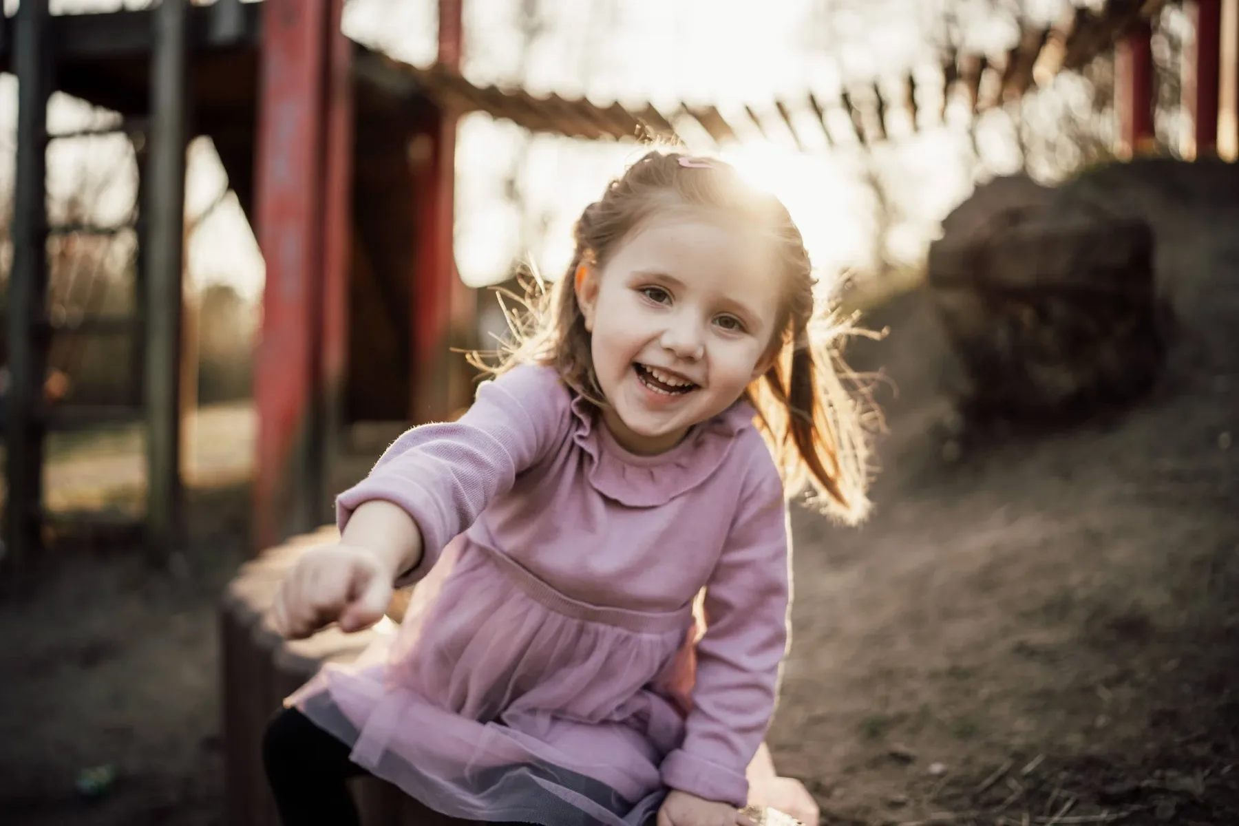 Kita-Fotografie: Mädchen im rosa Pullover lacht im Abendlicht auf dem Spielplatz