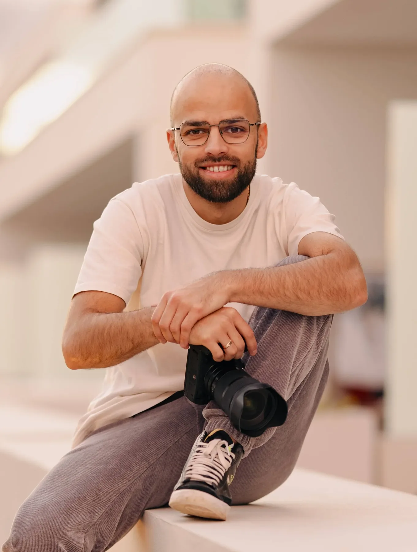 Fotograf sitzt in einem hellen Raum, die Kamera auf dem Knie