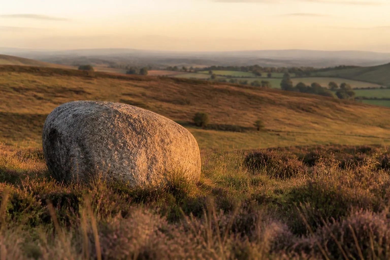 Heide- und Feldlandschaft mit einem großen Findling im Vordergrund